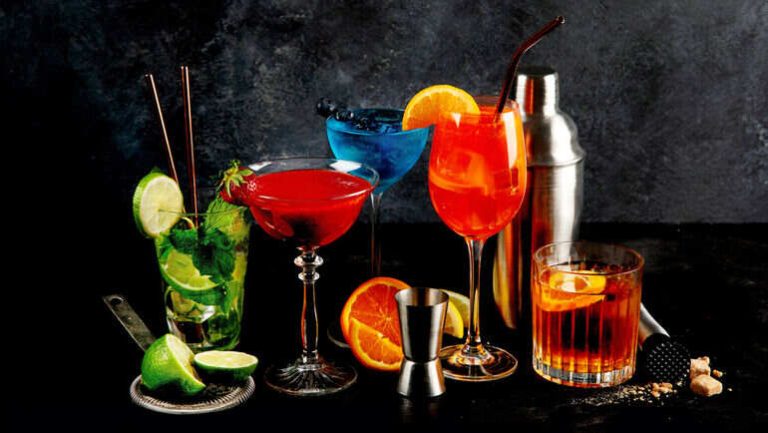 Assorted colorful beer cocktails with garnishes and a shaker