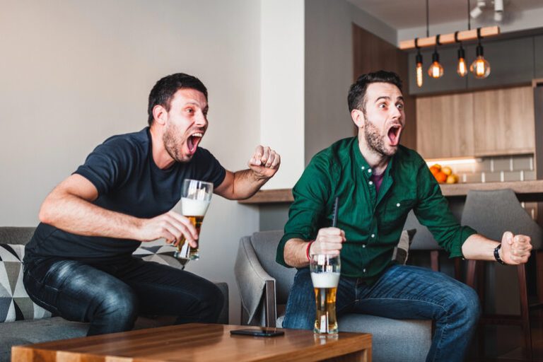 Friends excitedly watching sports while drinking beer