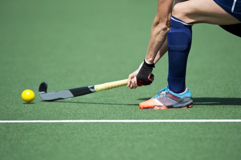 A Canadian hockey player passing a ball with a hockey stick