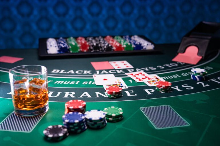 A blackjack table with playing cards and a glass of beer